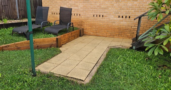 A restored courtyard with fresh paving beside a brick wall