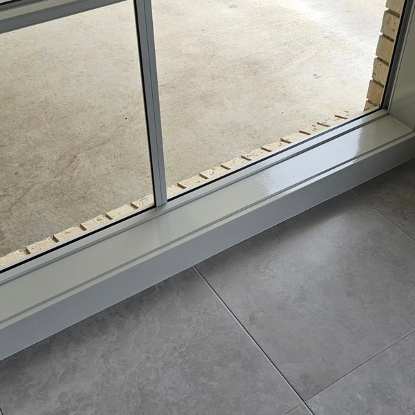 A tiled interior floor with freshly painted skirtings